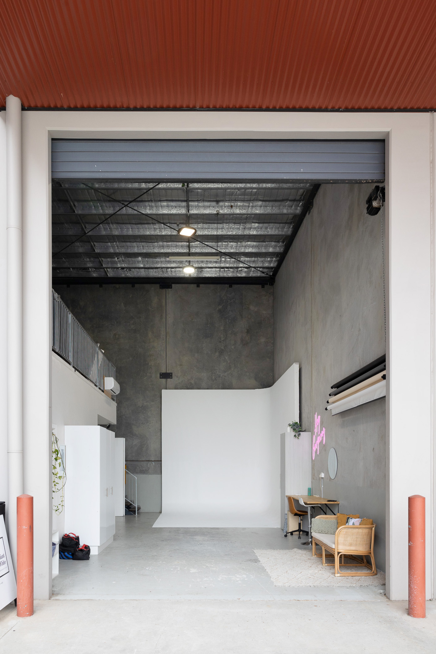 view of brilliant white studio from outside the open double storey roller door showing the cyc and paper backdrops