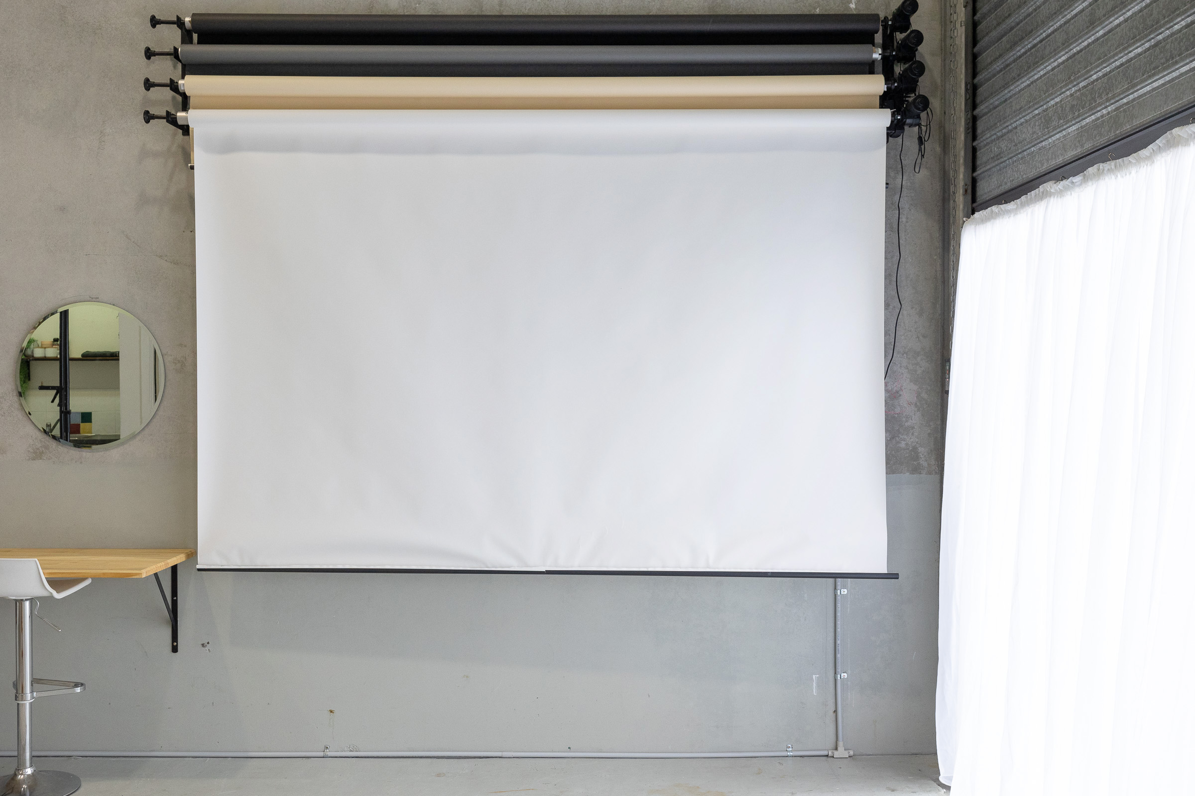 photography studio with 2.7m wide paper backdrop rolls and sheer curtain with daylight through roller door